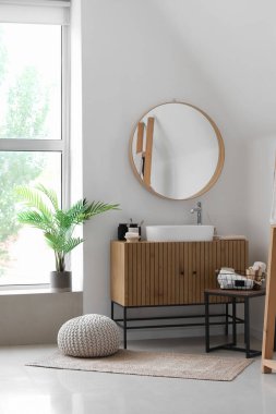 Lavabo kasesi ve banyo aksesuarları banyonun içindeki ahşap dolapta.