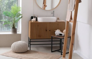 Lavabo kasesi ve banyo aksesuarları banyonun içindeki ahşap dolapta.