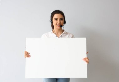 Işık arka planında boş posteri olan kadın teknik destek ajanı