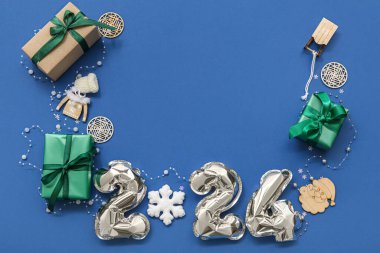 Folyo balonlardan, hediyelerden ve renk arkaplanındaki Noel süslemelerinden oluşan 2024 figürlü kompozisyon