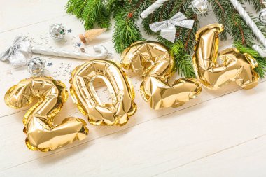 Figür 2024 folyodan yapılmış balonlar, Noel süslemeleri ve beyaz ahşap arka planda köknar dalları, yakın plan