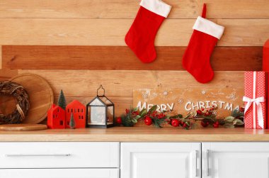 Ahşap duvarın yanında Noel süsü olan beyaz mutfak tezgahı.