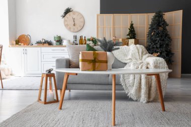 Açık uzay mutfağının içi gri kanepe, sehpa ve Noel dekoruyla dolu.