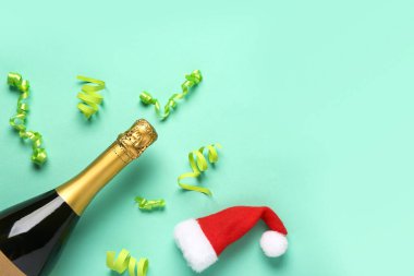 Şampanyalı kompozisyon, Noel şapkası ve turkuaz arka planda kurdeleler.