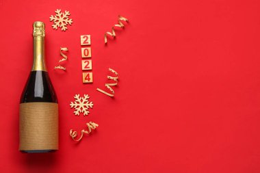 Şampanya şişeli Noel kompozisyonu, 2024 metni ve kırmızı arka planda dekor.
