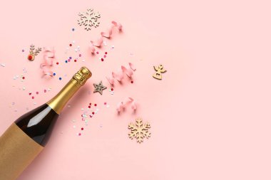 Pembe arka planda bir şişe şampanya ve dekor ile Noel kompozisyonu
