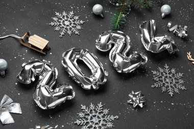 Figür 2024 folyo balonlardan ve siyah arka planda topları olan Noel ağacı dalından yapılmıştır.