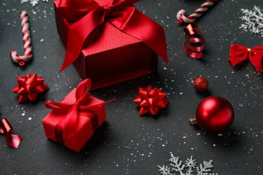 Noel baloları hediye kutuları ve siyah arka planda şeker kamışları.
