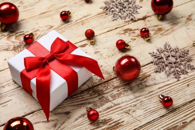 Hediye kutulu Noel baloları ve beyaz ahşap arka planda kar taneleri.
