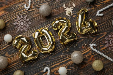 Noel topları, kar taneleri ve tahta zemin üzerinde şeker kamışları olan folyodan yapılmış 2024 model.