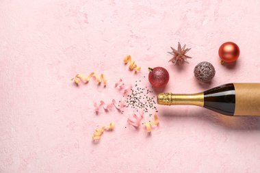 Pembe arka planda bir şişe şampanya ve dekor ile Noel kompozisyonu