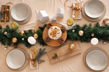 Mutfaktaki yemek masasında pasta ve yanan mumlarla Noel ayarları, üst manzara.