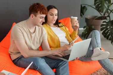 Genç programcılar ofiste dizüstü bilgisayarla çalışıyorlar.