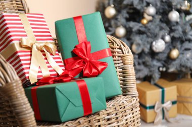 Oturma odasında hasır koltukta Noel ağacı olan hediye kutuları, yakın plan.