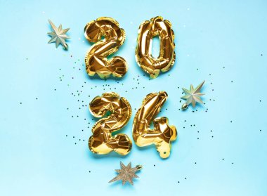2024 numaralı altın folyo balonları ve mavi arka planda Noel yıldızları