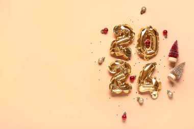 Şekil 2024 balonlardan, Noel süslemelerinden ve turuncu arka planda konfetilerden yapılmıştır.