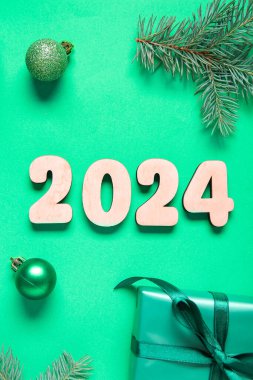Noel topları ve yeşil arka planda hediye kutusuyla 2024
