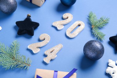 Şekil 2024, mavi arka planda Noel süslemeleri ve hediye kutusu var.