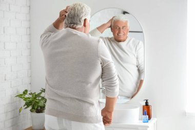 Evdeki aynaya bakan kıdemli adam.