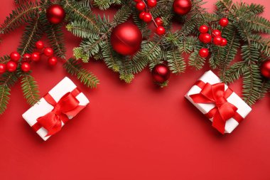 Kırmızı arka planda hediye kutuları, toplar ve rowan olan Noel ağacı dalları