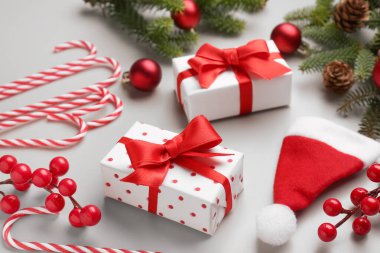 Noel ağacı dalları hediye kutuları, toplar ve gri arka planda Noel Baba şapkası