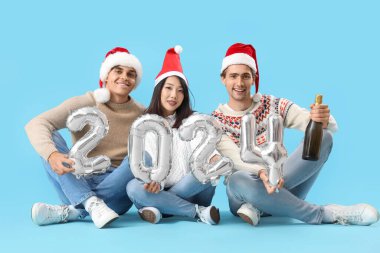 2024 model balonları olan genç arkadaşlar ve mavi arka planda şampanya.