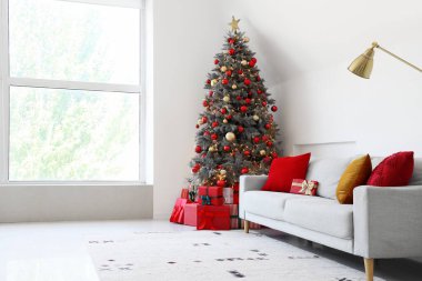 Gri kanepesi ve Noel ağacının altında hediye kutuları olan şenlikli bir oturma odası.