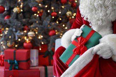 Noel Baba Noel arifesinde çantasından hediye alıyor. Kapatın.