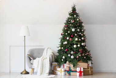 Gri koltuklu ve Noel ağacının altında hediye kutuları olan şenlikli oturma odasının içinde.