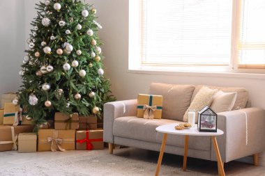 Gri kanepesi ve Noel ağacının altında hediye kutuları olan şenlikli bir oturma odası.