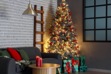 Gri kanepesi, kahve masası ve Noel ağacının altında hediye kutuları olan şenlikli oturma odasının içinde.