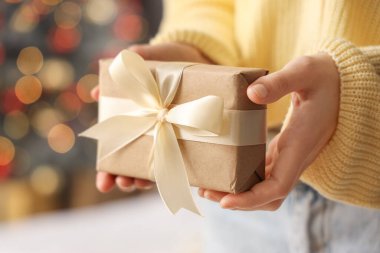 Noel arifesinde elinde hediye kutusu olan kadın, yakın plan.