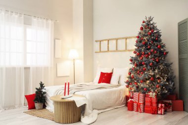 Şenlikli yatak odasının içinde rahat bir yatak ve Noel ağacının altında hediyeler.