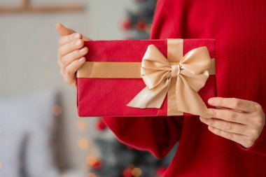 Noel arifesinde elinde hediye kutusu olan kadın, yakın plan.