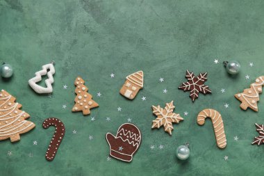 Farklı Noel kurabiyeleri ve yeşil arka planda süslemeleri olan kompozisyon