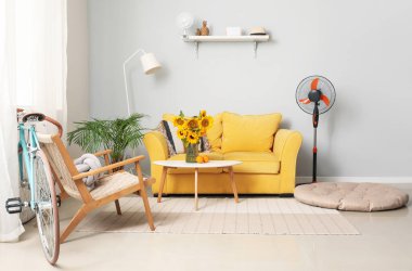 Oturma odasının içinde kanepe, bisiklet ve vantilatör var.