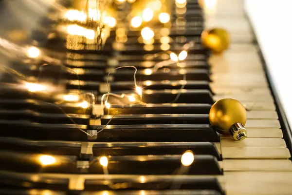 ピアノの鍵の上に光るライトが付いているクリスマスボール クローズアップ — ストック写真