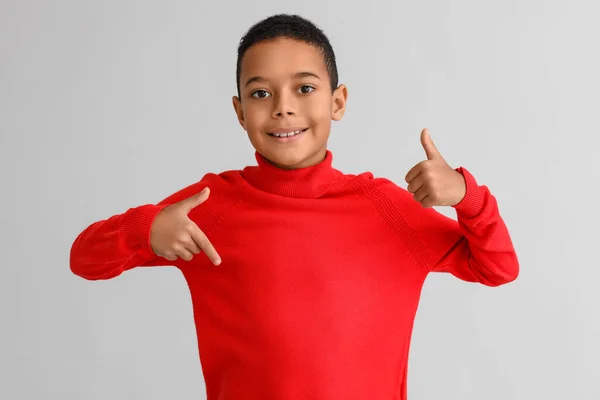 かわいい アフリカ系アメリカ人の男の子 暖かいセーター 明るい背景に親指を示す — ストック写真