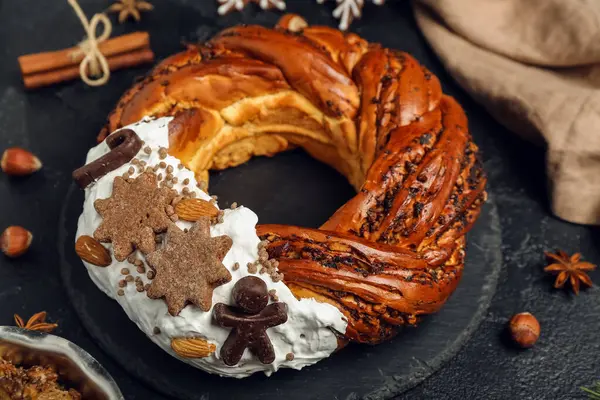 Karanlık arka planda lezzetli Noel pastası çelengi olan tahta, yakın plan.