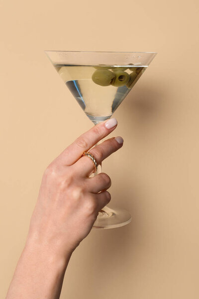 Woman with glass of martini on beige background