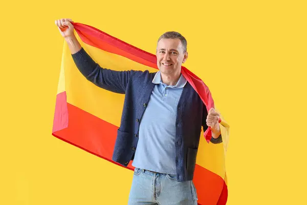 Mature man with flag of Spain on yellow background
