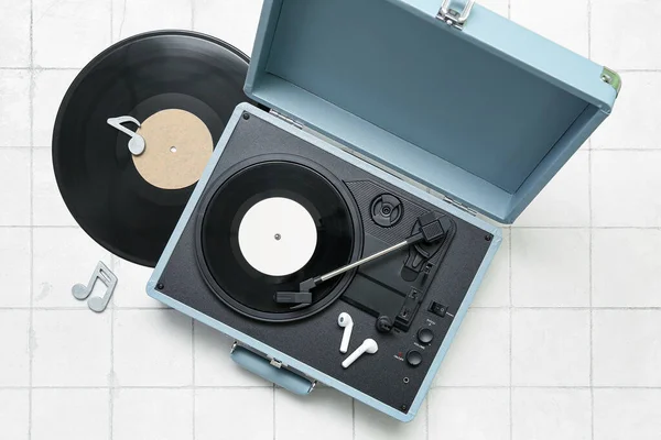 Record player with vinyl disks, earphones and note signs on white tile background