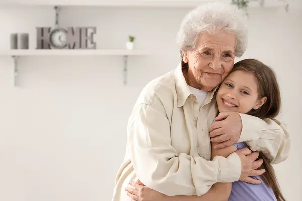 Little girl with her grandmother hugging at home
