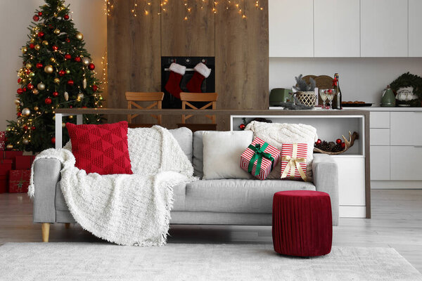 Interior of light open space kitchen with grey sofa and Christmas decor