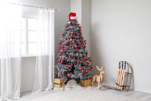装饰圣诞树 有红球 礼品盒 木鹿和白墙附近的雪橇 — 图库照片