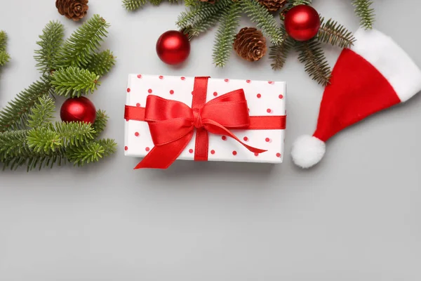 圣诞树分枝 有礼品盒 球和灰色背景的圣诞老人帽 — 图库照片
