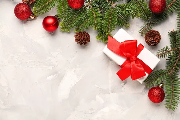 Beyaz grunge arka planında hediye kutusu ve topları olan Noel ağacı dalları
