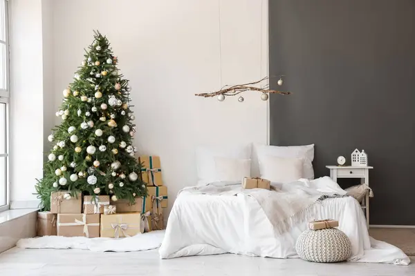 有舒适床 挂装饰和圣诞树的喜庆卧室的内部 — 图库照片