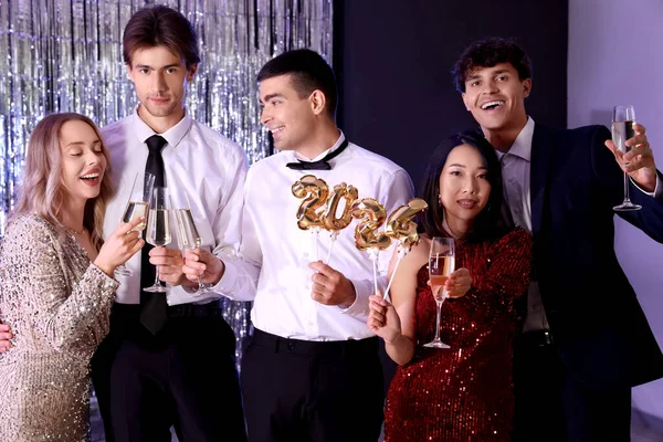 Group of young people with champagne and figure 2024 at Christmas party