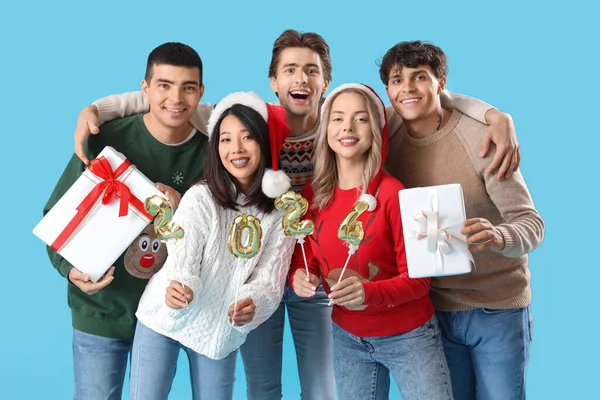 Group of young people with figure 2024 and Christmas presents on blue background